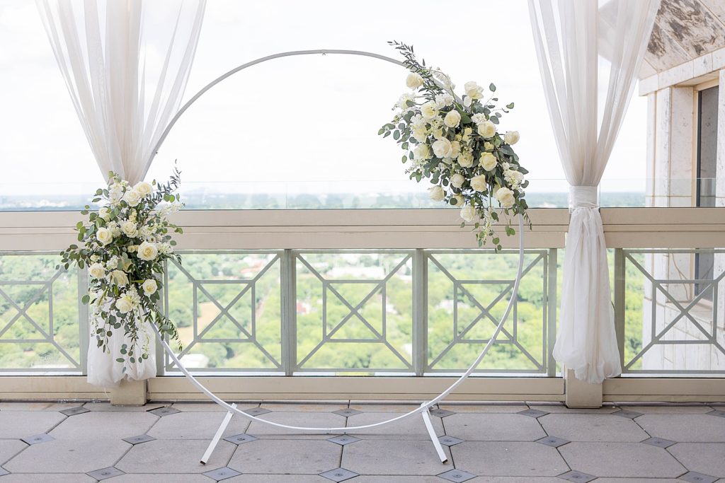 ceremony arch decorated with white roses and greenery 