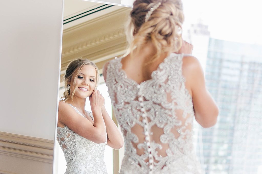 bride putting on earrings overlooking downtown Atlanta through the large window
