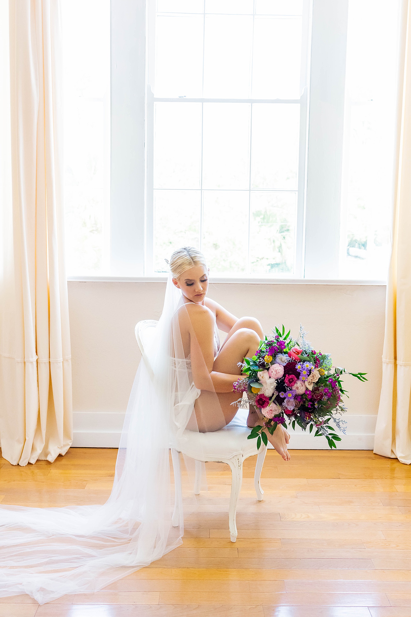 bride in white lingerie sitting in chair with bouquet from atlanta georgia lingerie store