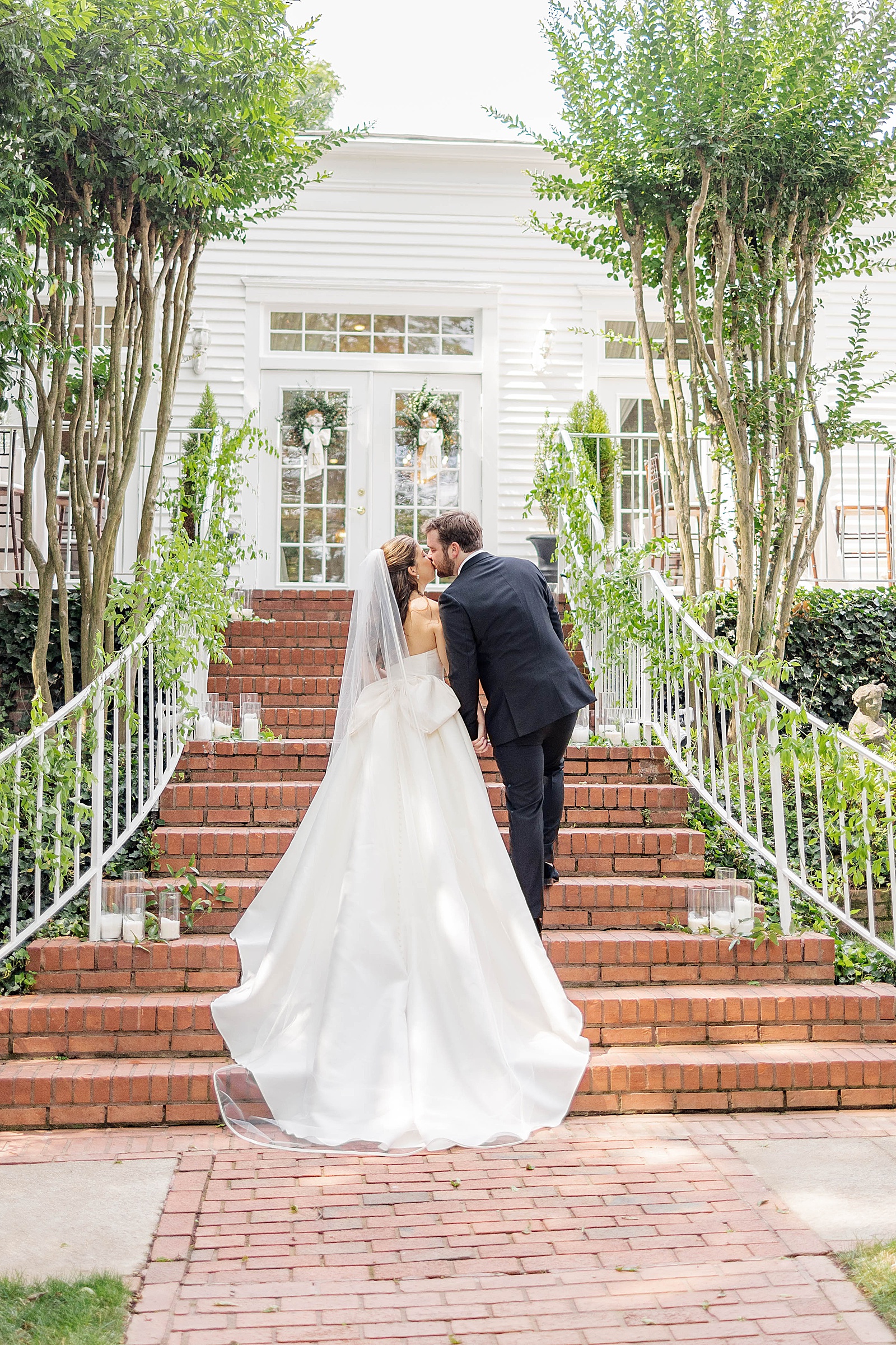 bride and groom kiss on the stairs at the Whitlock Inn, a charming wedding venue in marietta, georgia