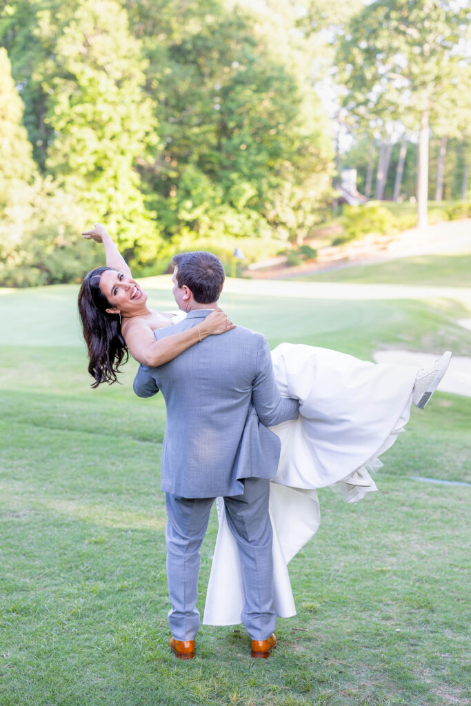 groom carrying bride at the golf course at country club of the south
