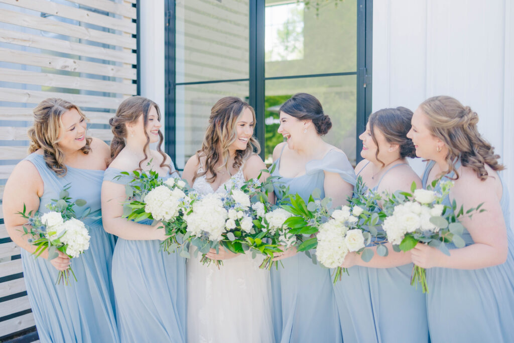 bridesmaids standing together with white bouquets smiling at the bride