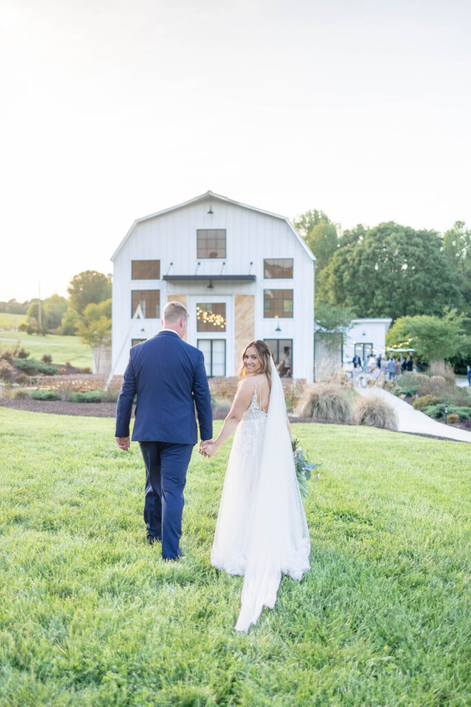 bride and groom holding hands and walking towards Barn South wedding venue