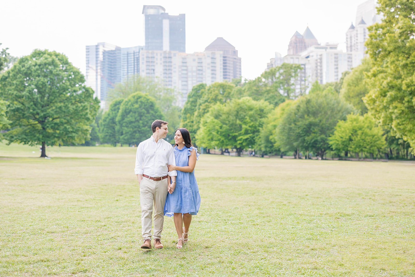 couple walking through piedmont park in atlanta during the springtime for engagement photos