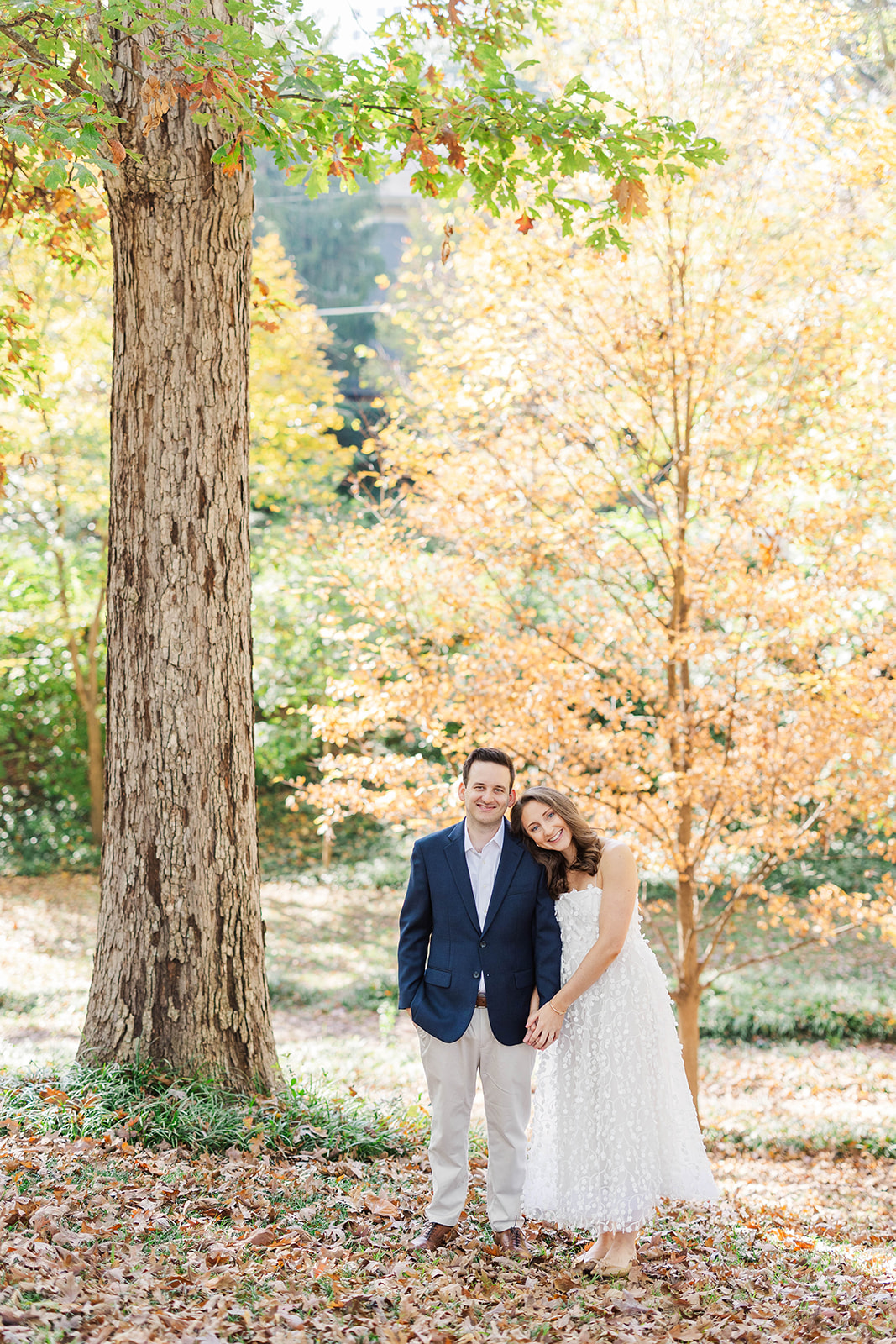 coupe poses in front of autumn colored tree in winn park during engagement photo session