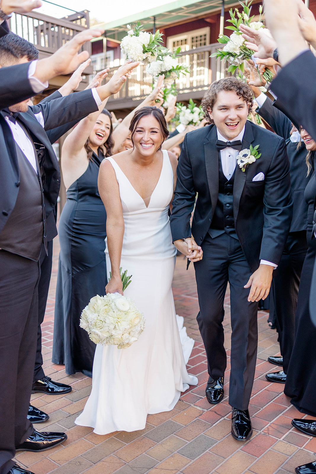 Newlyweds laugh while running under an arch of hands