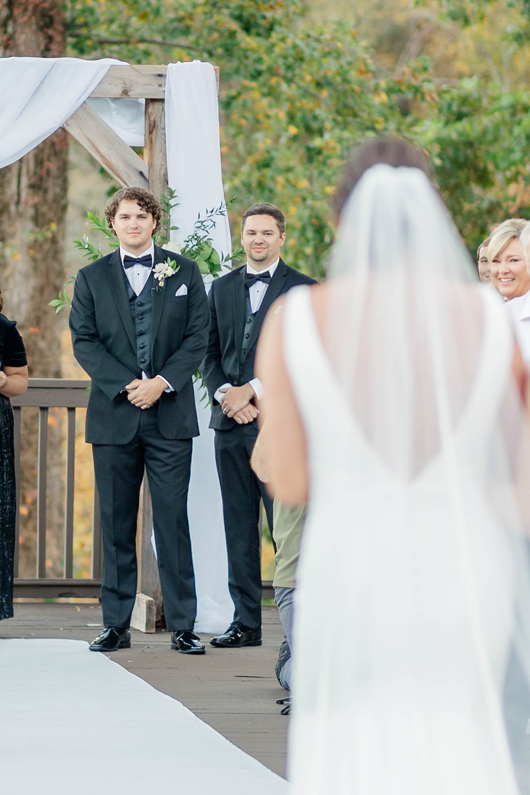 A groom waits in his black tux for his bride to walk down the aisle