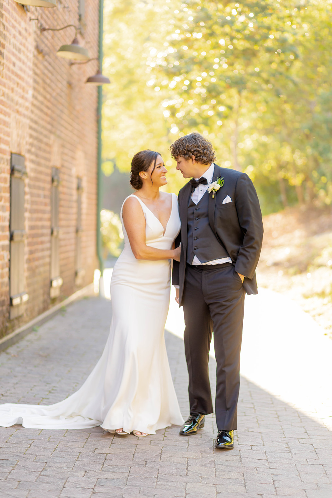 A bride and groom giggle while walking hand in hand in a back alley