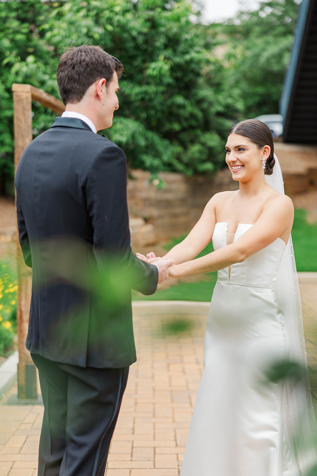 A happy bride and groom hold hands during their first look on the patio at their Upstairs Atlanta Wedding