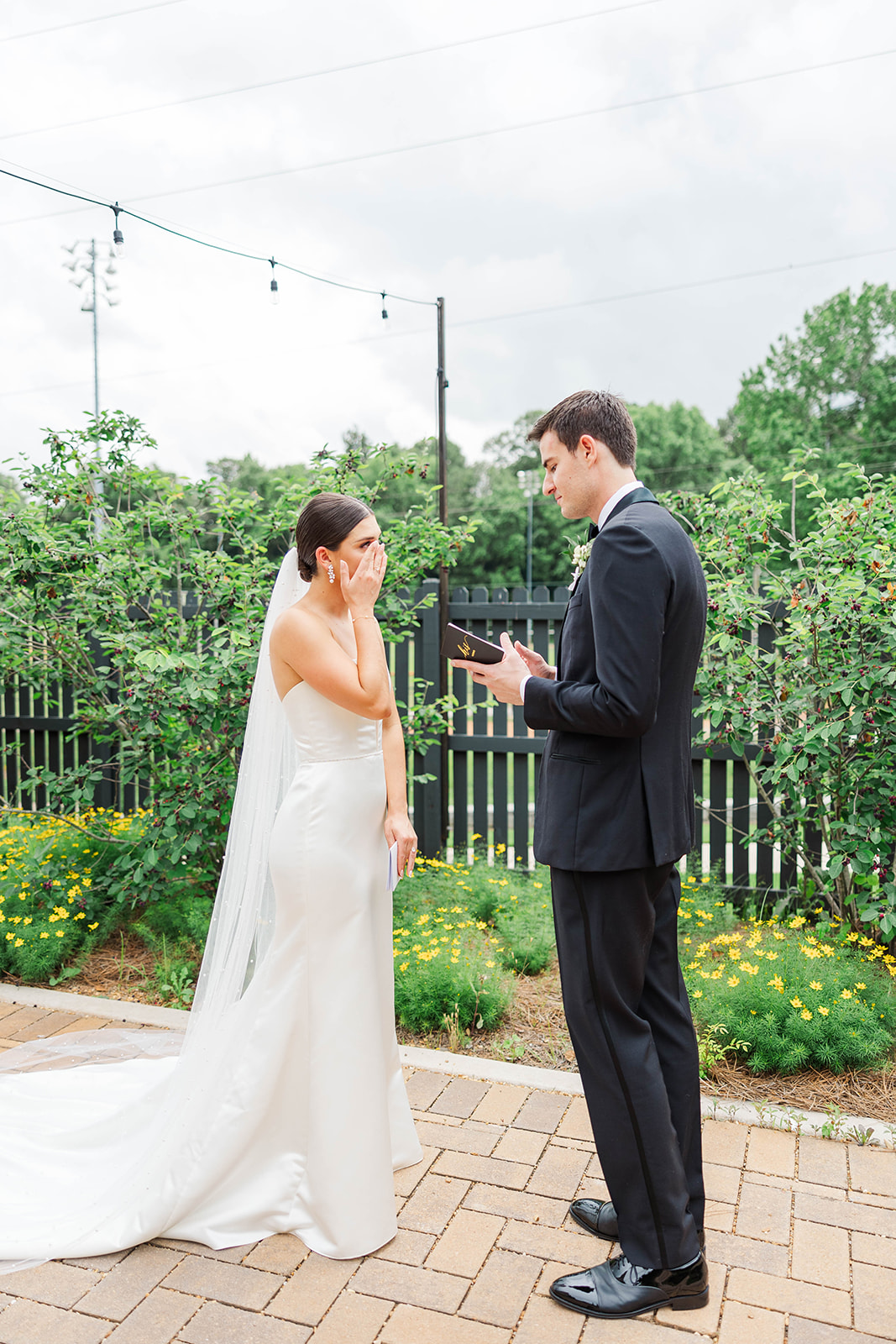 A bride cries as her groom reads a note during their first look at their Upstairs Atlanta Wedding