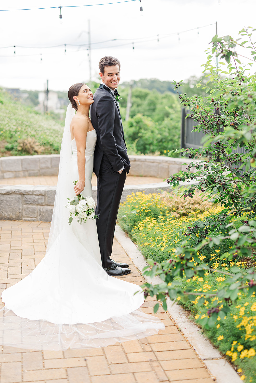 A bride stands behind her groom smiling in the garden at their Upstairs Atlanta Wedding