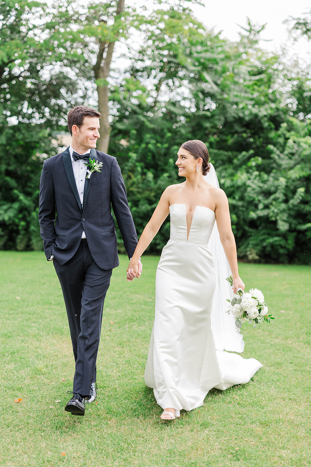 Newlyweds hold hands while smiling at each other in the lawn of their Upstairs Atlanta Wedding