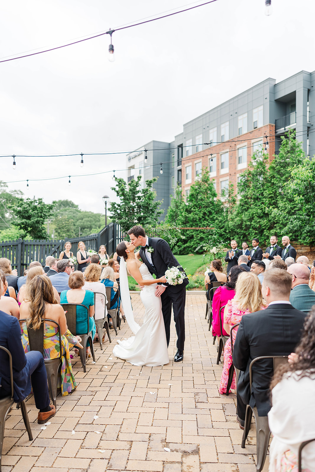 Newlyweds kiss while exiting up the aisle of their outdoor Upstairs Atlanta Wedding ceremony
