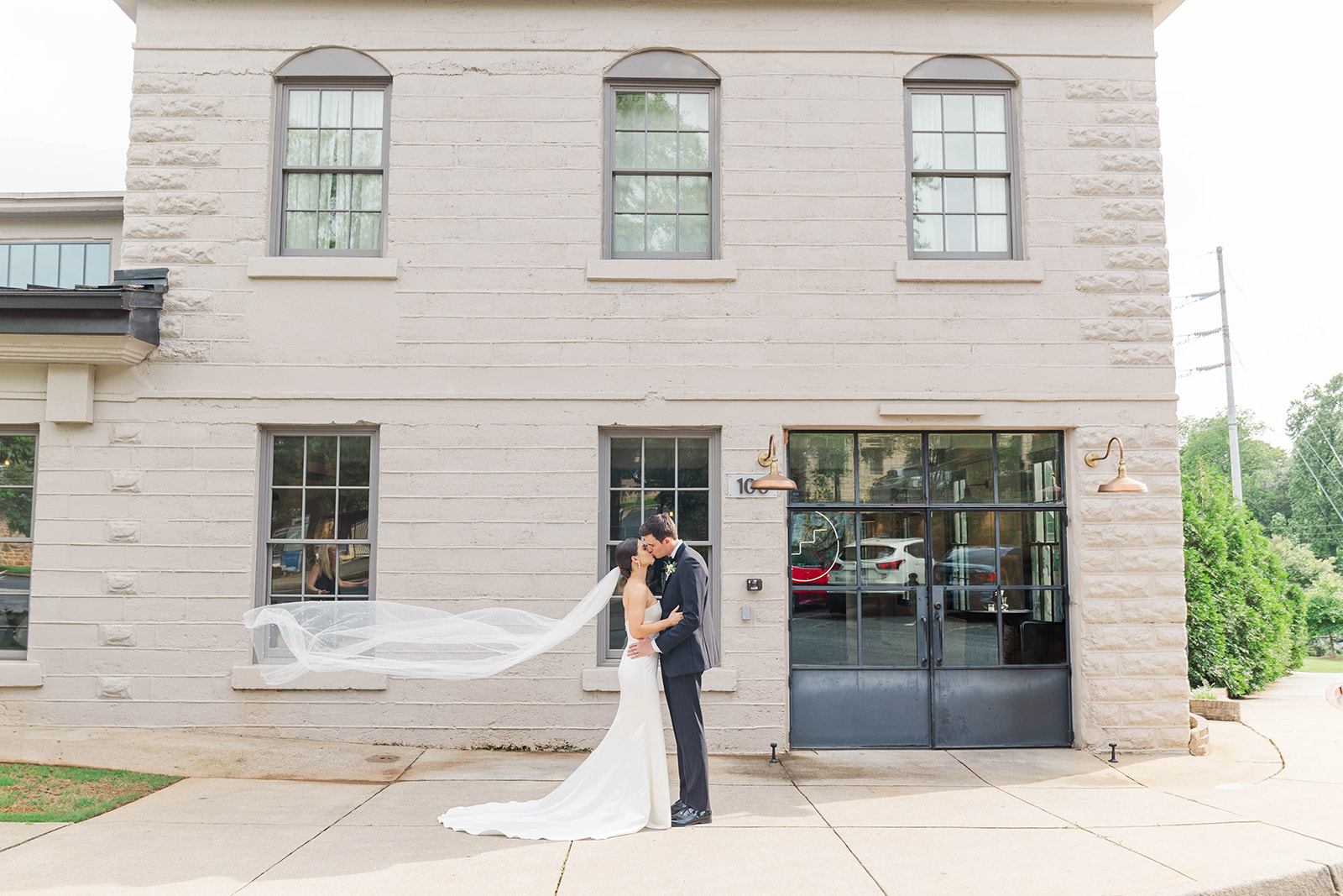 Newlyweds kiss in the windy sidewalk outside the Upstairs Atlanta Wedding venue