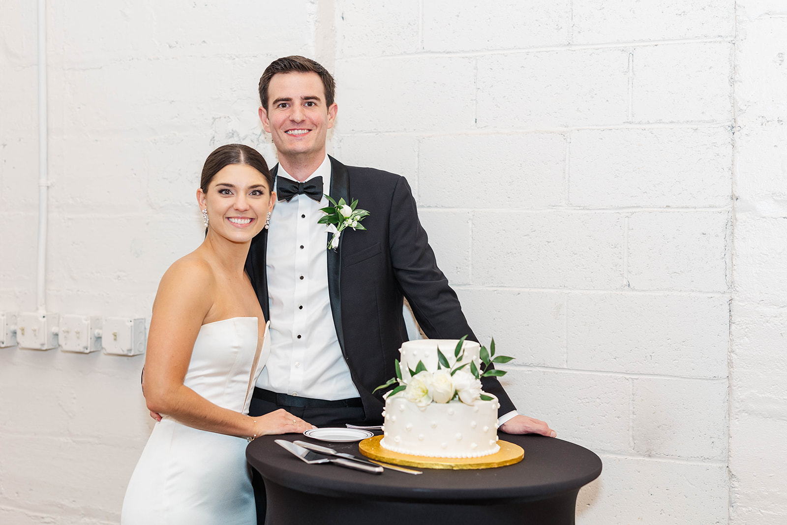 Happy newlyweds smile while preparing to cut the cake