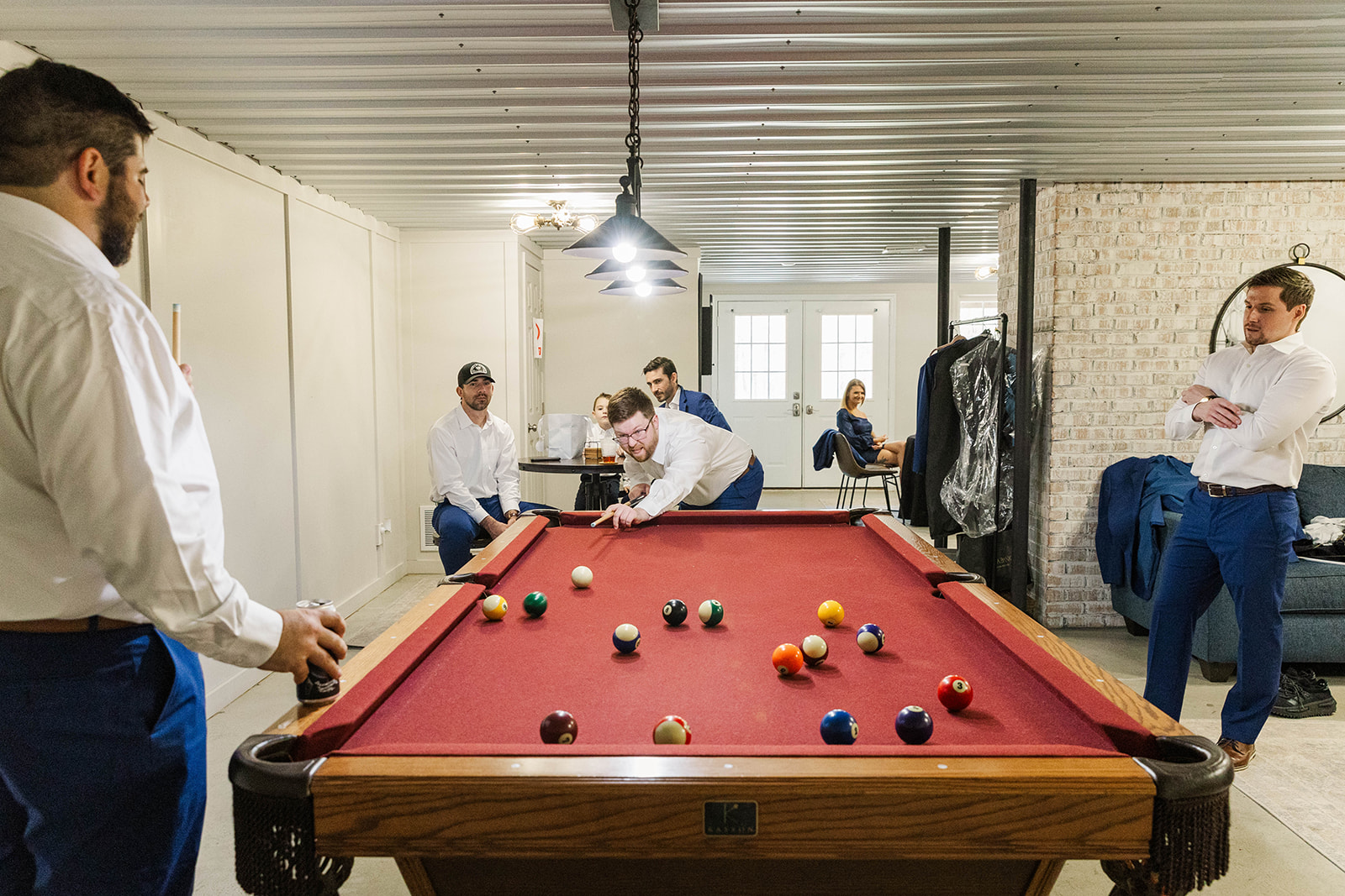 A groom plays pool with his groomsmen while getting ready