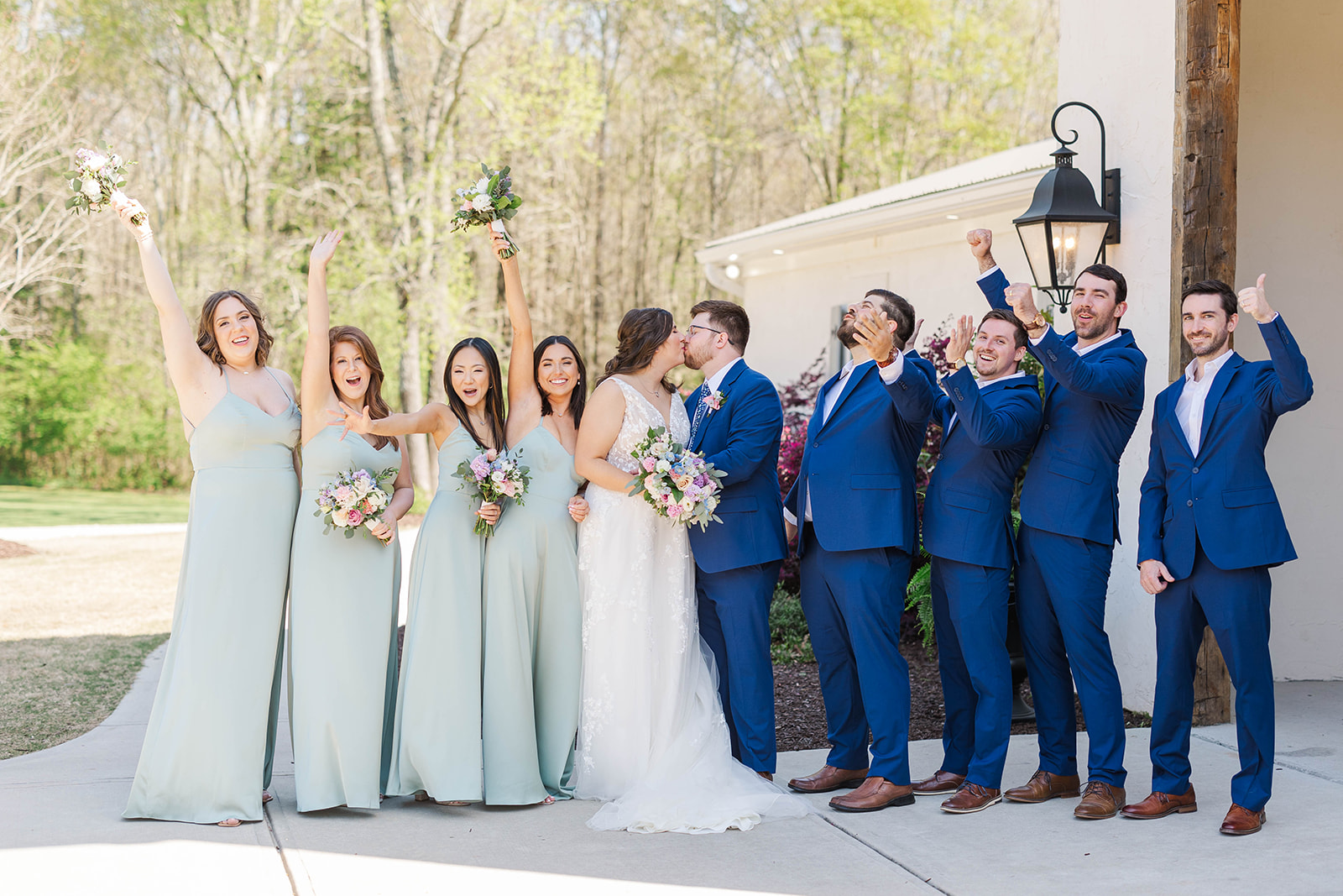 Newlyweds kiss as their wedding party cheers on the front patio of White Fox Cottage