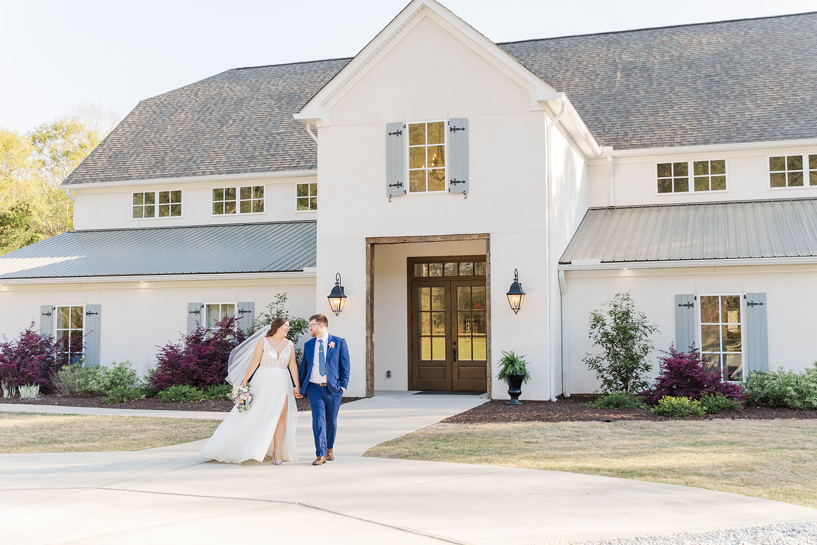 Newlyweds smile at each other while walking in the front sidewalk at White Fox Cottage