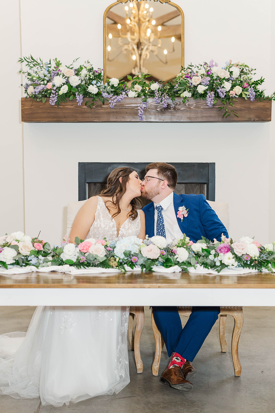 Newlyweds kiss at their flower covered head table at White Fox Cottage