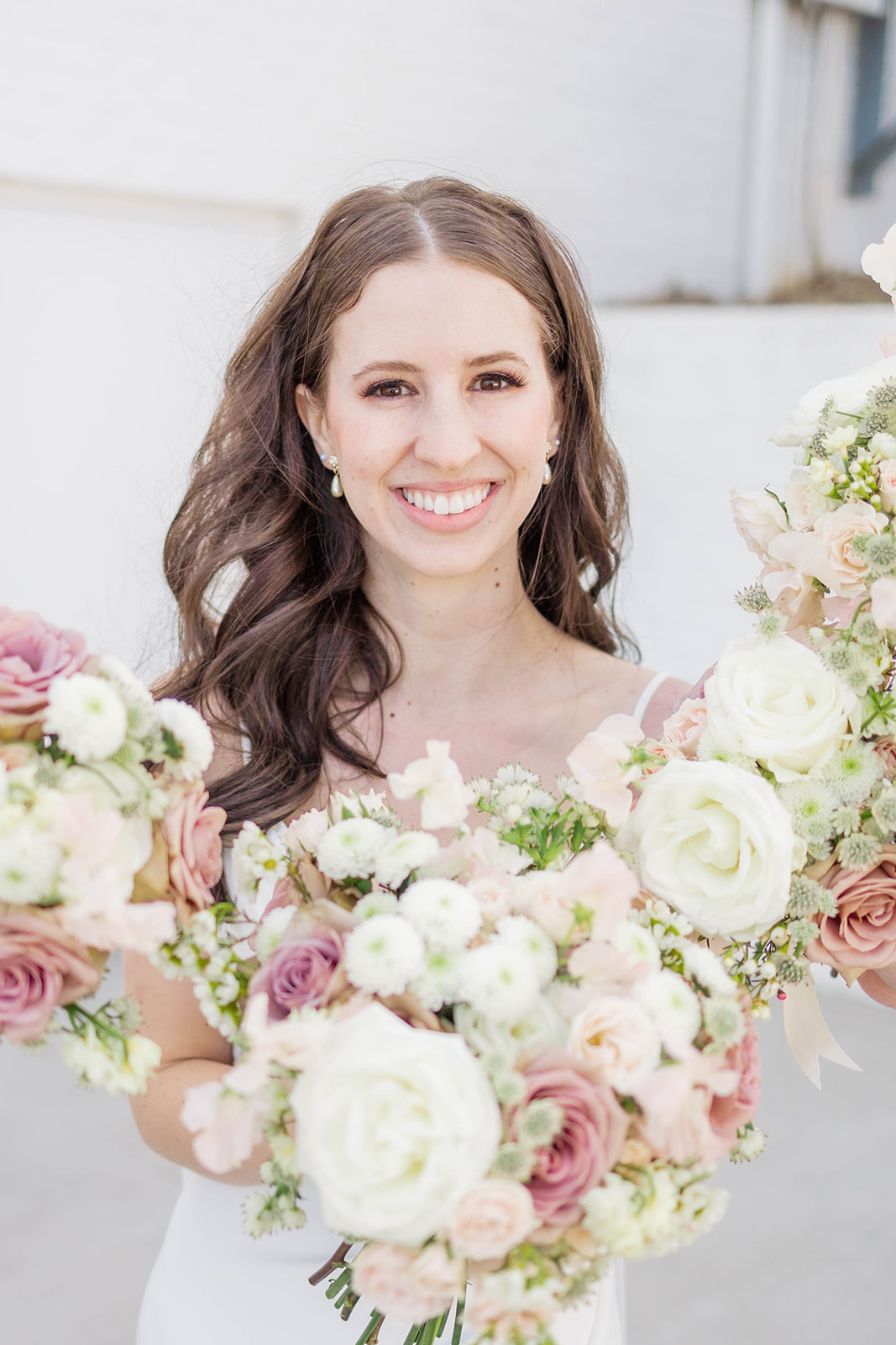 A happy bride smiles with a white and pink bouquet at one of the country club wedding venues in Atlanta, GA