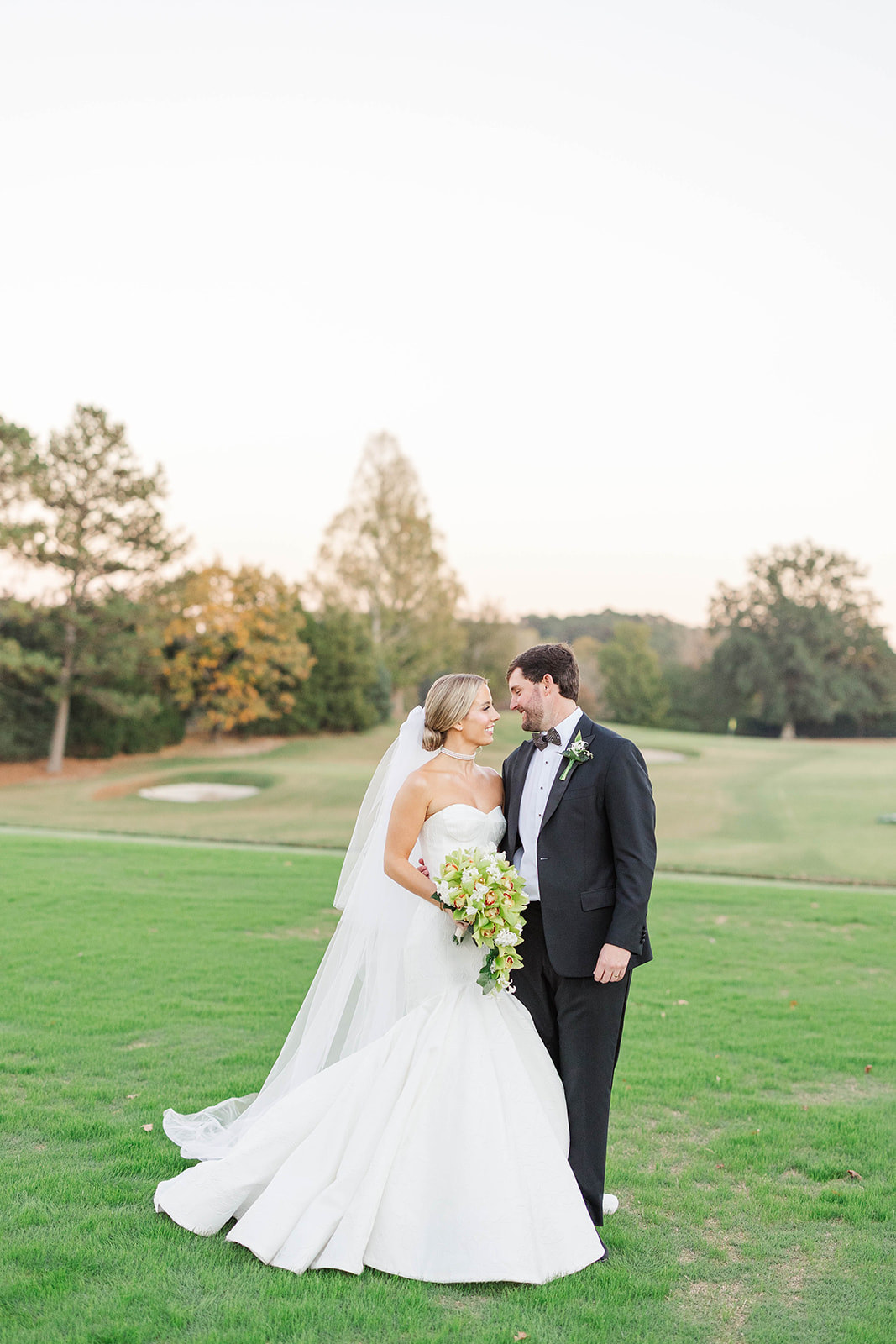 Newlyweds smile at each other while standing on a fairway at one of the country club wedding venues in Atlanta, GA