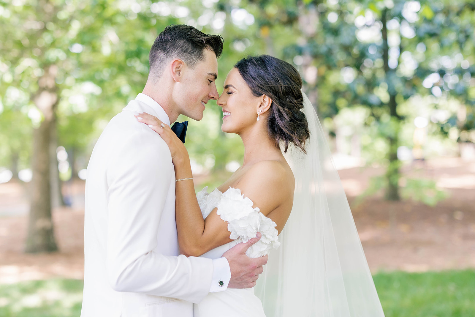Newlyweds touch noses in a manicured lawn outside one of the country club wedding venues in Atlanta, GA