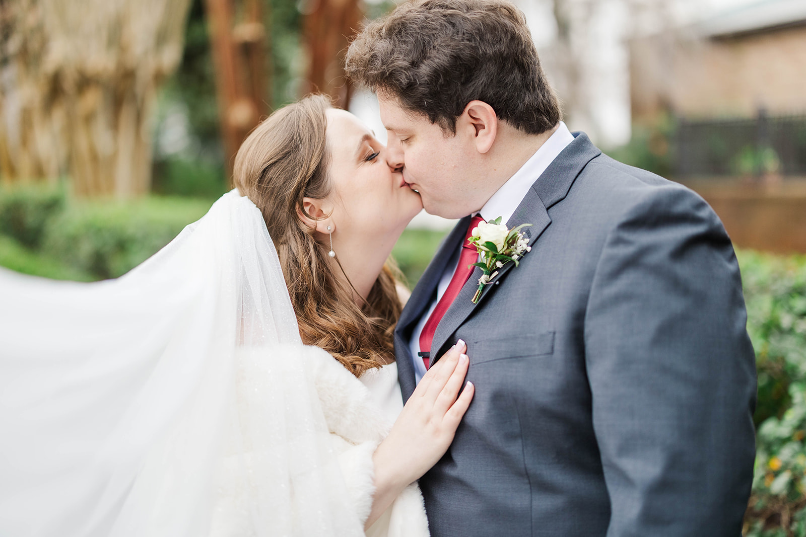 Newlyweds kiss in the garden as the veil flies around them