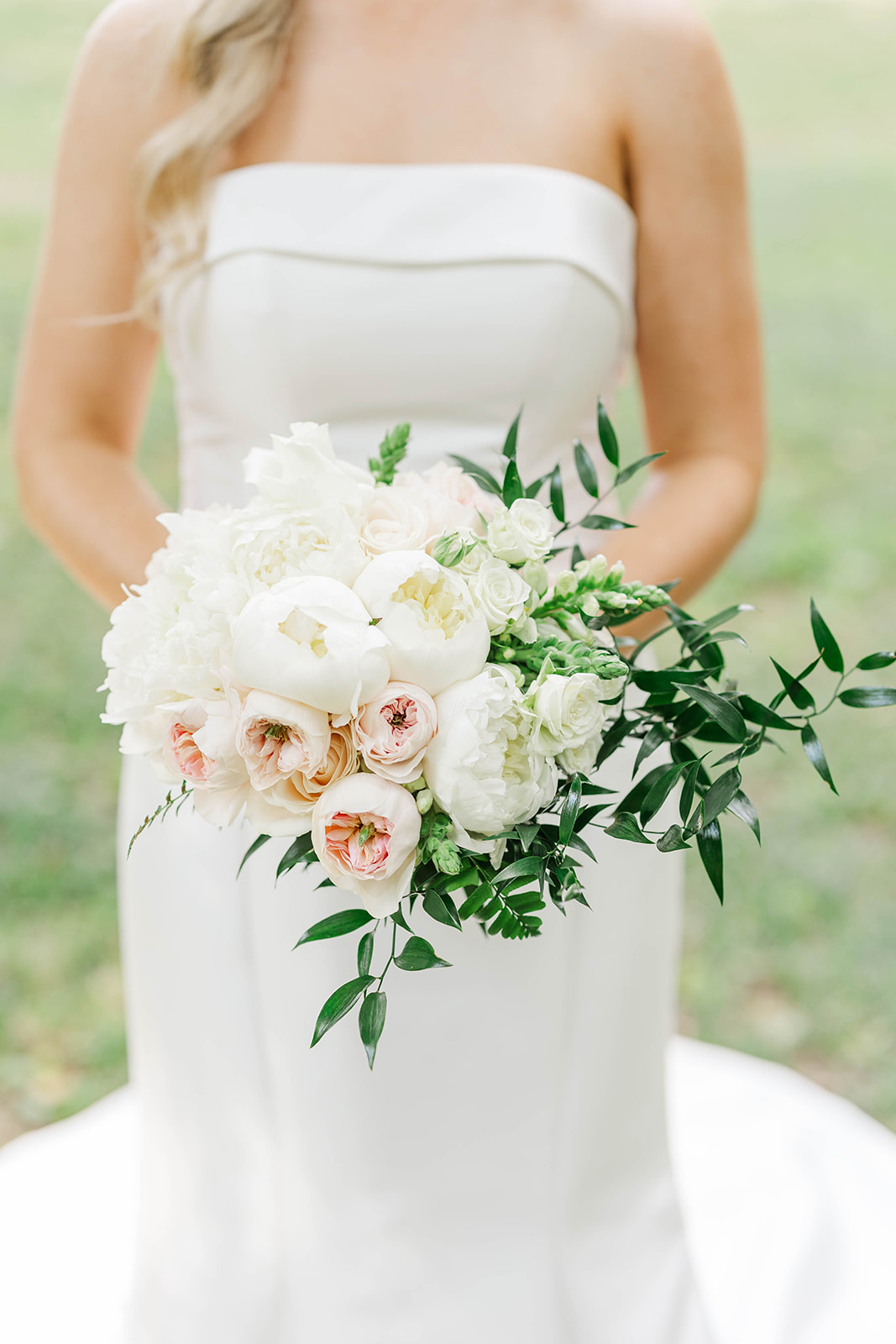Details of a bride's bouquet as she holds it in a lawn
