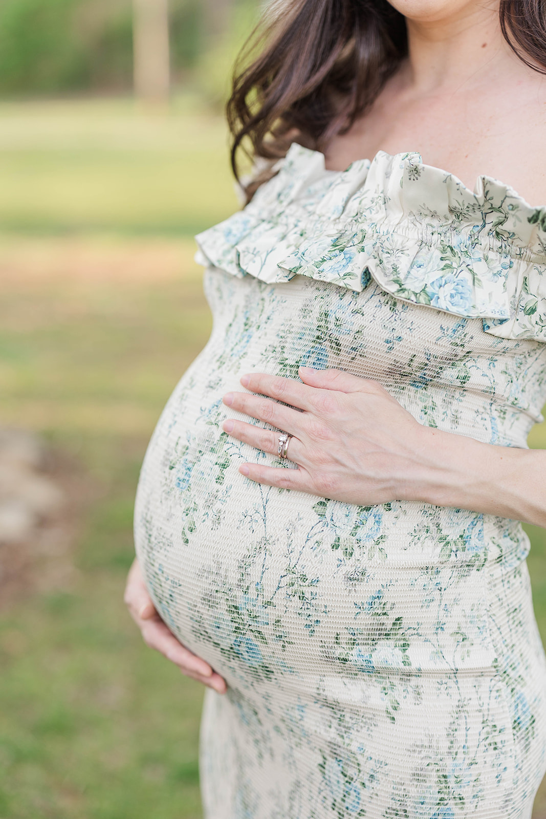 Details of a mother to be in a floral print dress holding her bump after some prenatal yoga in Marietta, GA
