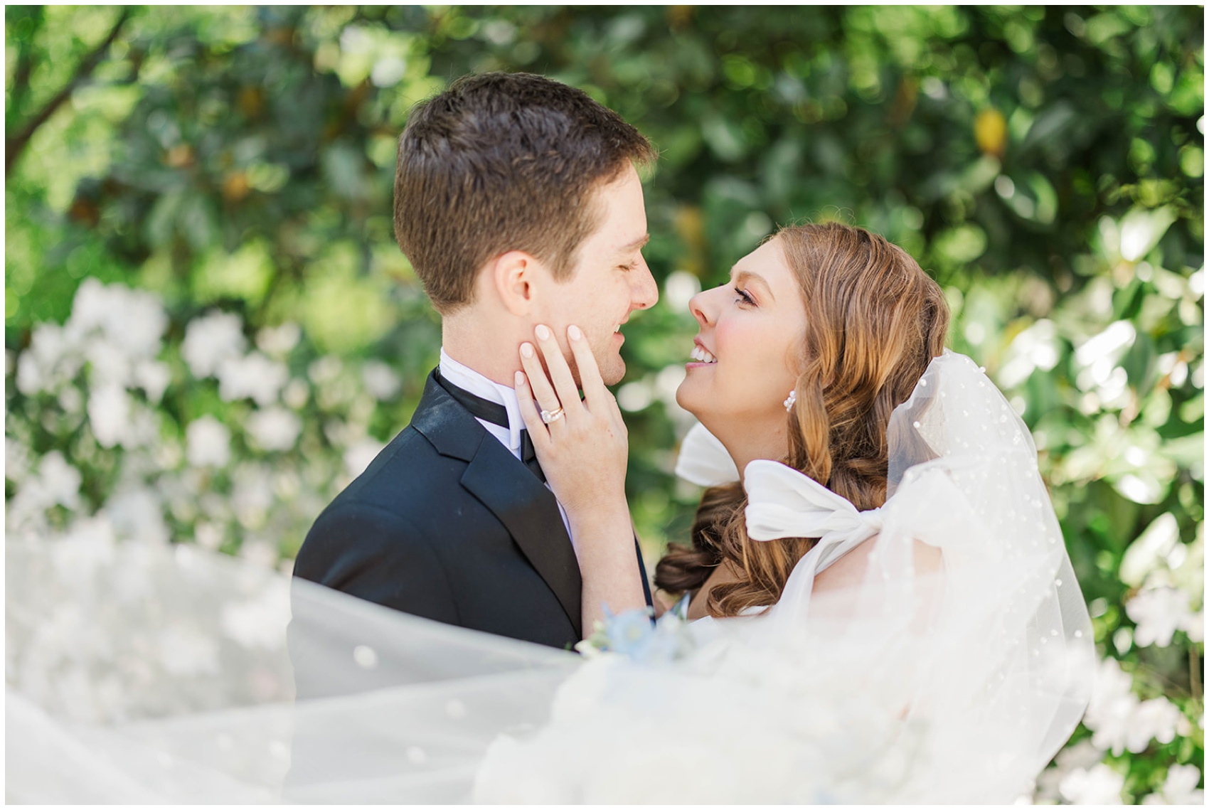 A bride leans in for a kiss with her hand on her groom's cheek