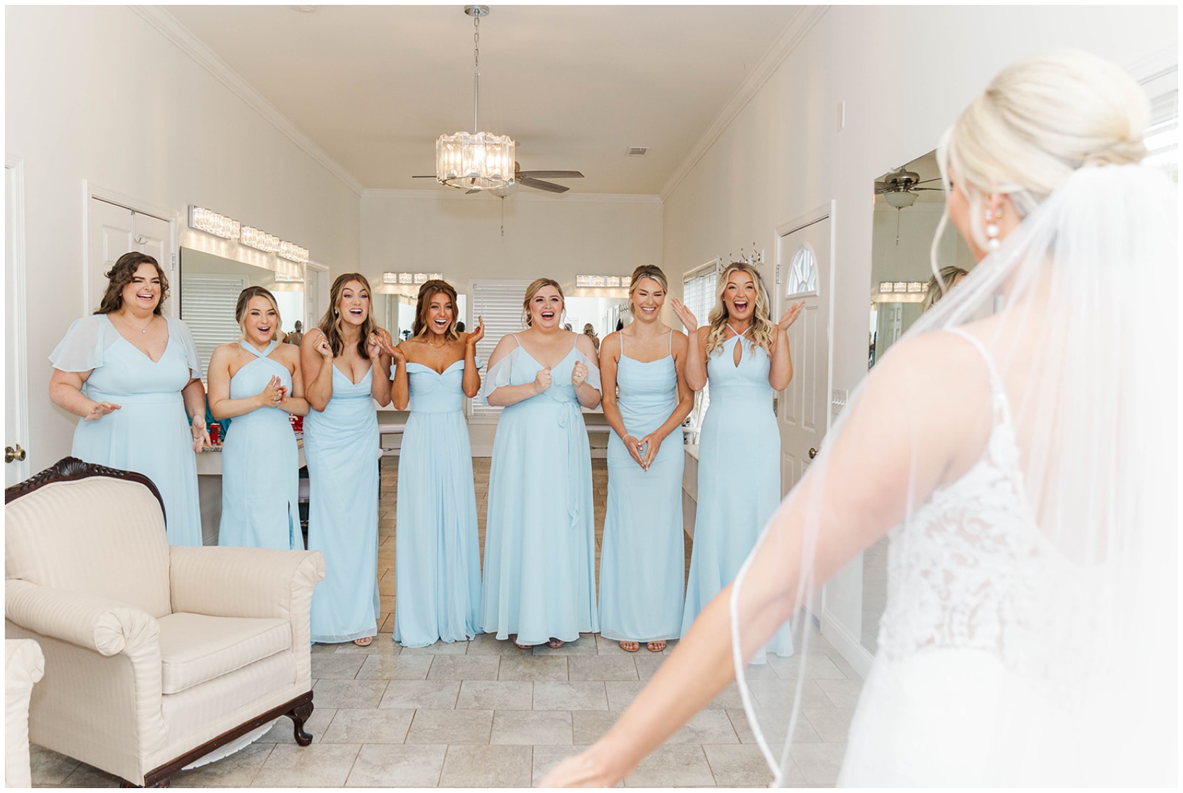 Bridesmaids in blue dresses cheer when seeing the bride for the first time