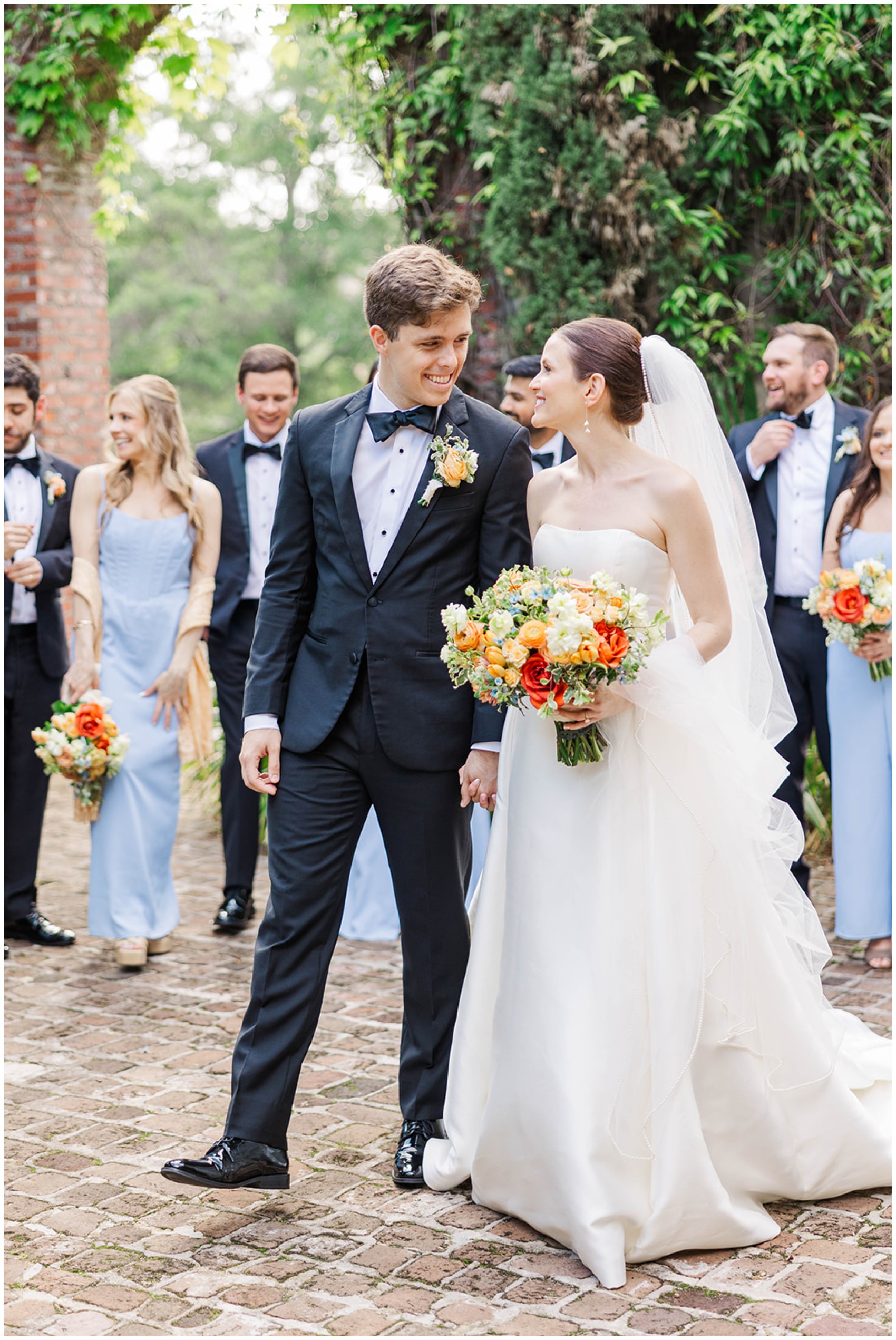 Newlyweds hold hands while walking with their wedding party at their Summerour Studio wedding