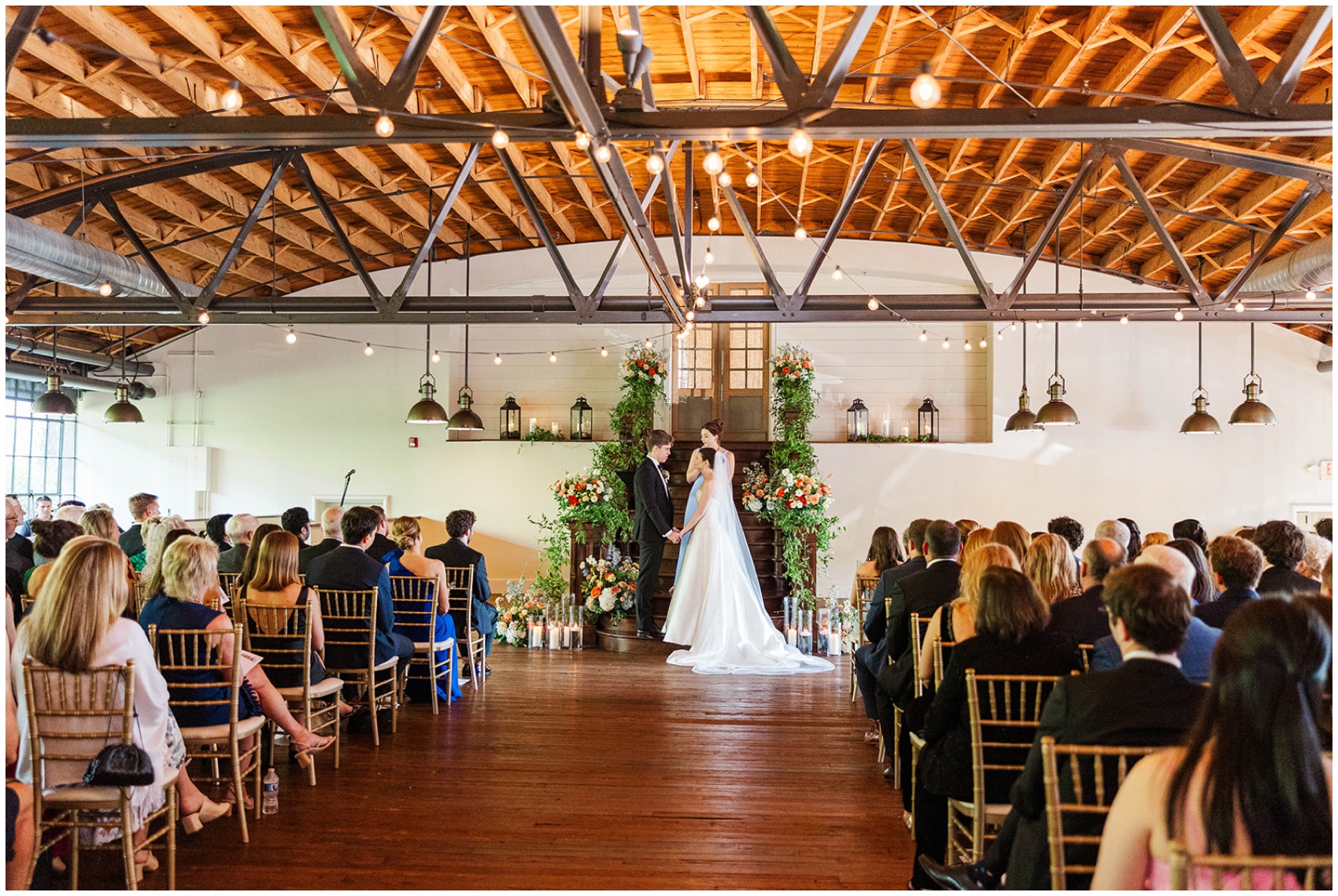 A look down the aisle during a wedding ceremony as bride and groom hold hands