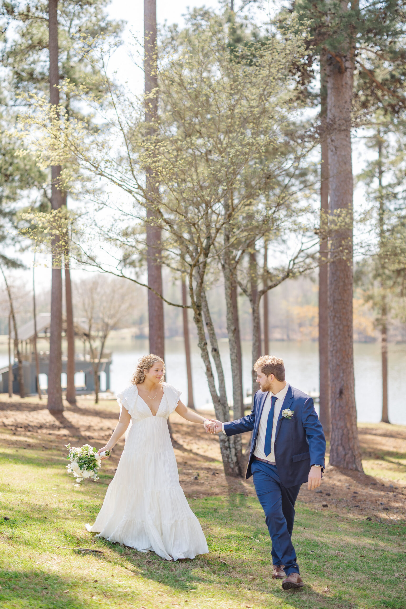 bride and groom walking along the shaded tree area at Sandy Creek Barn in Lake Oconee